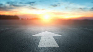 An asphalt road stretches into the distance with a painted white arrow, symbolizing planning and the concept of forward movement.